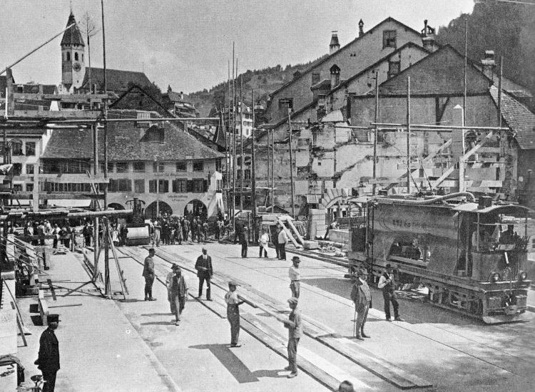 SW-01​On June 1st 1923, a test was carried out using the town’s Hartmann steam roller and the STI water sprinkler tram. In the background is the Stadkirche Thun.